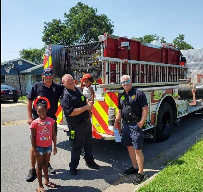 photo of firefighters and children in front of fire truck