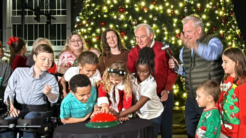 photo of a group of people pushing button to light the tree